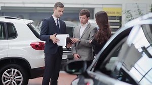 clip-12987245-car-salesman-shows-young-couple-information-about