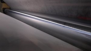 clip-1037718893-rolls-non-woven-fabric-being-pushed-into-tube