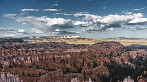 4k Timelapse movie film clip of Bryce Canyon with clouds and shadows moving across the landscape of bryce canyon in utah in summer with snow on the ground and green trees with blue skies and fluffy