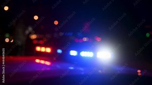 Blurred Police and ambulance emergency lights flash at night. Flashlights. Crime scene. Car accident and traffic jam. Flashing blue and red lights and signals on patrol car.