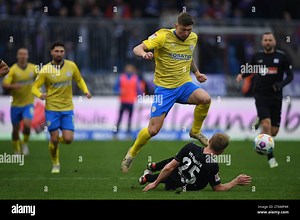 11 November 2023, Lower Saxony, Brunswick: Soccer: Bundesliga 2, Eintracht Braunschweig - VfL Osnabrück, Matchday 13, Eintracht Stadium. Braunschweig's Luc Ihorst plays against Osnabrück's Niklas Wiemann (on the ground). Photo: Swen Pförtner/dpa - IMPORTANT NOTE: In accordance with the regulations of the DFL German Football League and the DFB German Football Association, it is prohibited to utilize or have utilized photographs taken in the stadium and/or of the match in the form of sequential im