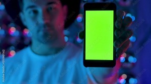 Young Creative Man Hand Holding Mobile Telephone with Vertical Green Screen. Front View Man which Hold Smartphone with Chroma Key for Present App or Video Mockup. Use Modern Mobile Phone Greenscreen