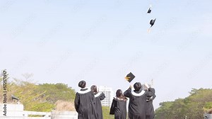 Happy students running and throwing graduation hats in air