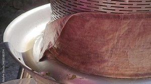 The process of making homemade grape wine. Hydraulic press in the process of squeezing grape juice. Juice from white grapes drips into a container.