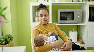 Mother and son sitting on table breastfeeding baby at dinning room