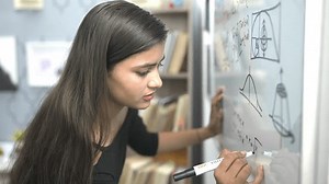 Indian teen student worried write formula think of sums on white board with marker pen at educational institute. Schoolgirl face problem while solving mathematics addition questions in classroom