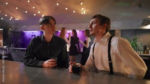 Two men friends talking in night bar. Young joyful men resting in club, talking chatting drinking alcohol cocktails, having fun together. Party enjoyment, man friendship, relaxing people concept.