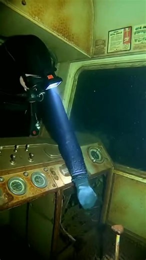Diving deep into the abyss reveals a chilling, sunken secret: the submerged cabin of an old train wreck. As the diver navigates the eerie, rusty control panel, the past feels terrifyingly close. This is a moment where history and nature collide, creating an underwater ghost town. The first 2 lines must include a strong hook: **Wait till you see what’s inside this forgotten conductor’s cab!** The diver attempts to interact with the broken controls, stirring up the sediment and the mystery surroun