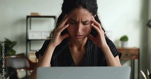 Distressed businesswoman looks at laptop feels frustrated by business failure, close up. Tired female sit at workplace desk suffers from headache during computer task. Stress, problems at work concept