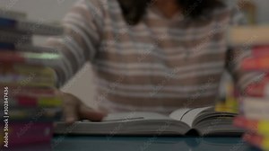Girl flip a page and reading a textbook with stack of books on the table at home. Education concept.