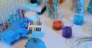 Lab technician experiments mixing different solutions and using colored test strips to assess pH levels simultaneously