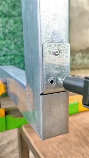 Fastening a metal frame joint using a screw and electric drill for secure structural connection