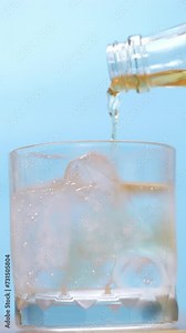 4K footage vertical video Front view SLO MO CU, Pouring alcohol into the soda of ice with blue background.