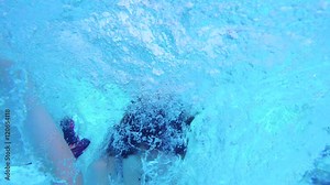 Underwater footage of two kids jumping into a swimming pool and diving in the water