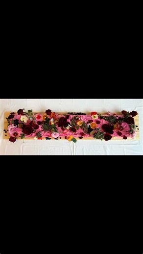 80th birthday with this vibrant, whimsical cake! 🎂 Inspired by the trend of long wedding cakes, we created this 1.2-meter-long beauty featuring one side of vanilla and custard, and the other with indulgent salted caramel. Adorned with bold, textured buttercream in a rustic pink finish, the cake is topped with an abundance of fresh florals—roses, peonies, poppies, lilies—and fruits like passion strawberries, dried blood orange, lemon, and blueberries. The colors and textures combined to create a