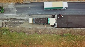 Construction work for road. Pavement machine laying fresh asphalt during highway construction