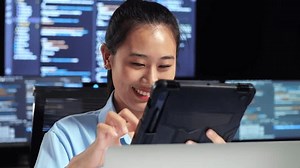 Cierre De La Programadora Asiática Con Tablet Mientras Escribe Código Por Una Laptop Con Varios Monitores Que Muestran La Base De Datos En Los Escritorios De La Ventana Terminal En La Oficina