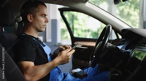 Mechanic using tablet pc at the repair garage service. Using digital tablet for car diagnostic. Interactive diagnostics software on an advanced computer