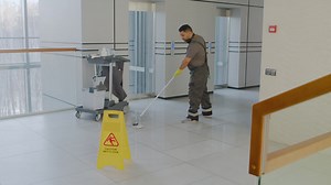 Free stock video - Distant view of arabic cleaning man cleaning with mope behind a wet floor warning sign