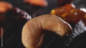 falling dried fruits in slow motion on a bamboo background, raisins, white raisins, almonds, nuts, cashews. Nuts fall on the table.