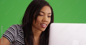 Close up over the screen view of black woman working on laptop computer on greenscreen. African American Millennial woman using pc on green screen background. 4k
