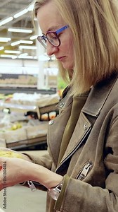 Woman examines fresh grapefruit in a grocery store, thoughtfully assessing her options. Vibrant produce emphasizes the importance of healthy eating choices