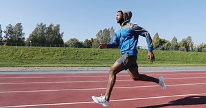Young black man running outdoors early in the morning. Afro-american male model training at the stadium.