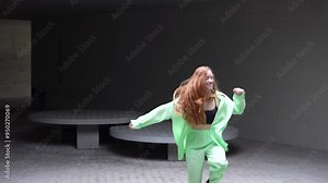 A vibrant and youthful woman wearing a neon green outfit dances with joy in a modern setting