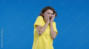 Frightened shocked woman afraid of something and screaming into camera with big eyes full of horror on blue background. Phobia, trouble, panic concept.