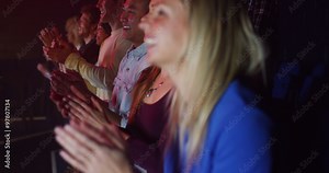 Young theatre audience give a standing ovation to the performers on stage