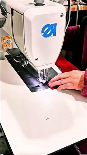 Guiding red fabric through industrial sewing machine for precise stitching