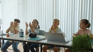Pan shot of group of diverse children clapping hands when thanking teacher for lesson at school