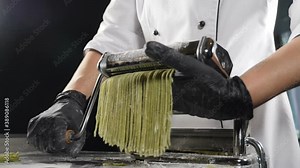 Traditional Italian cuisine. Making homemade pasta, close-up of chef makes pasta using steel machine. Fresh spaghetti pasta coming out of pasta machine, Rolling dough into thin noodles, Full hd