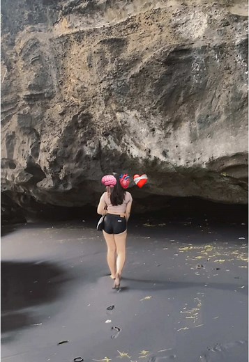 Woman Balancing Balloons on Black Sand Beach