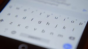 Finger touching virtual keys form a digital keyboard of a touchscreen phone