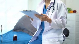 Female medicine doctor hand holding silver pen writing something on clipboard close up. Ward round, patient visit check, medical calculation and statistics concept.