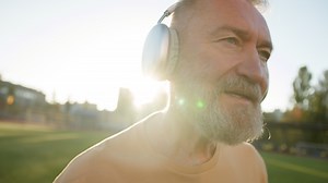Close up old Caucasian man grandfather modern tech walking going with headphones street outside city stadium training sportsman active lifestyle listen music songs elderly male leave sunbeam earphones