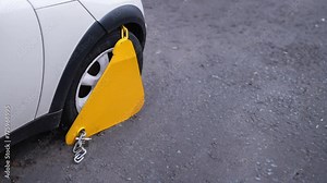 Looping Animation Of A Car In The Street Having A Clamp (Or Boot) Attached To Its Wheel, Then Removed