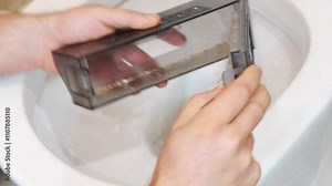 Men's hands use a brush to clean the vacuum cleaner container and throw the garbage down the toilet. cleaning and washing household appliances after cleaning.