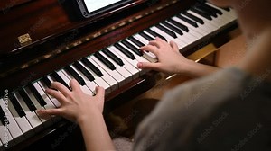 Playing a musical instrument under the light of a table lamp. Reading notes from an electronic tablet.