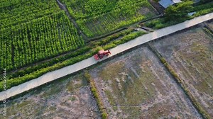 Aerial view of fields and agricultural parcels. Farmer in tractor preparing land with seedbed cultivator as part of pre seeding activities in early spring season of agricultural works at farmlands.