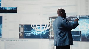 Black software expert focusing on programming language for innovation, reading binary code on terminal window. Reviews code development for data science. Modern futuristic coding life. Camera A.