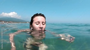 Girl spitting water into the camera in the sea, slow motion