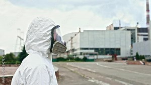 Profile of man scientist in protective suit and gas mask walking near rebuilt power station of Chernobyl. Exclusive dark tour to Chernobyl Zone and Prypiat city.