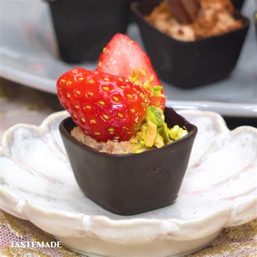 【製氷機で大量生産】ひとくちチョコカップムース🍫 製氷機×氷でかわいいチョコカップが作れちゃう！！！ お好みのトッピングで楽しめてバレンタインにもおすすめです💝🍫 ■材料 コーティングチョコレート 300g 生クリーム 100ml チョコレート 50g ドライストロベリー 適量 板チョコレート 適量 いちご 適量 ピスタチオ 適量 ■手順 【事前準備】 ・チョコレートは湯せんで溶かす。 ・チョコレートムースを作る。 ・溶かしたチョコレートに生クリームの半量を加えてよく混ぜ、残りの半量の生クリームはホイップする。 ・氷水につけながらチョコレートを混ぜ、とろみがついたら少しずつホイップを加えていく。 ・出来たら絞り袋に入れる。 1. 製氷機に水を入れ、櫛などを入れて固まるまで凍らす。 2. 溶かしたチョコレートに氷をくぐらせ、キッチンペーパーに乗せて固まるまで待ったら氷を抜く。 3. チョコレートムースをチョコレートカップに搾る。 4. お好みのトッピングをする。 | Tastemade Japan