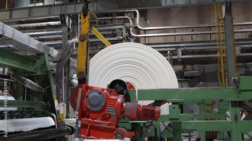 Modern paper mill, showing the final stages of cellulose paper production with huge rolls of paper move through an automated system of high-speed rollers and conveyors, static slow motion