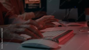Closeup of hands of unrecognizable diverse male and female IT professionals frantically typing commands on computer keyboards while trying to repel hacking attack on corporate network