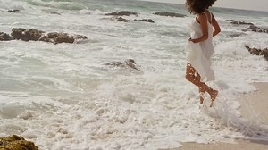 Side view of african american woman playing with sea water on the beach 4k Free Stock Video Footage