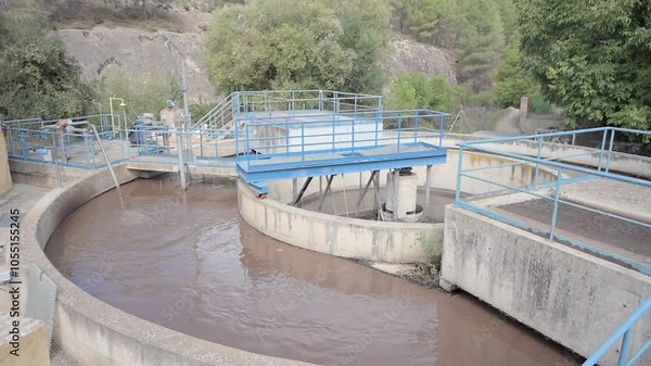 Industrial wastewater treatment facility with a prominent circular sedimentation tank, surrounded by greenery, highlighting environmental management and advanced water purification techniques