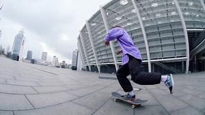 Focused skater guy jumping on skateboard at city street. Sporty hipster trying extreme trick outdoor in summer. Active skateboarder falling from skate near stadium in slow motion.